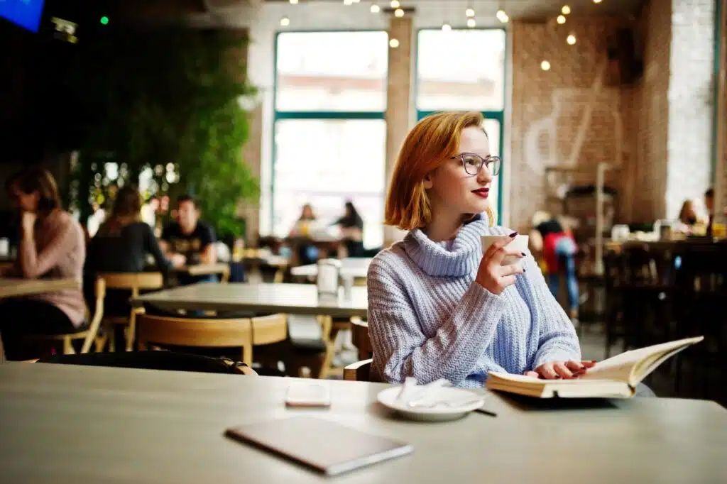 Cafe Names. A young woman in a cafe drinking coffee