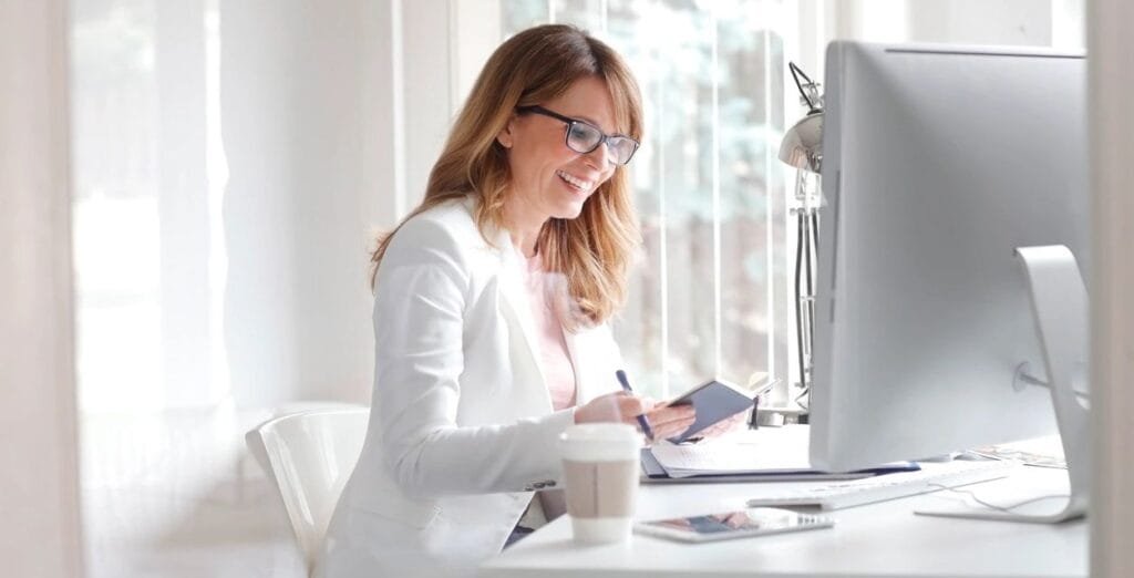 A woman at a desk with a computer learning how to form an LLC step by step online.