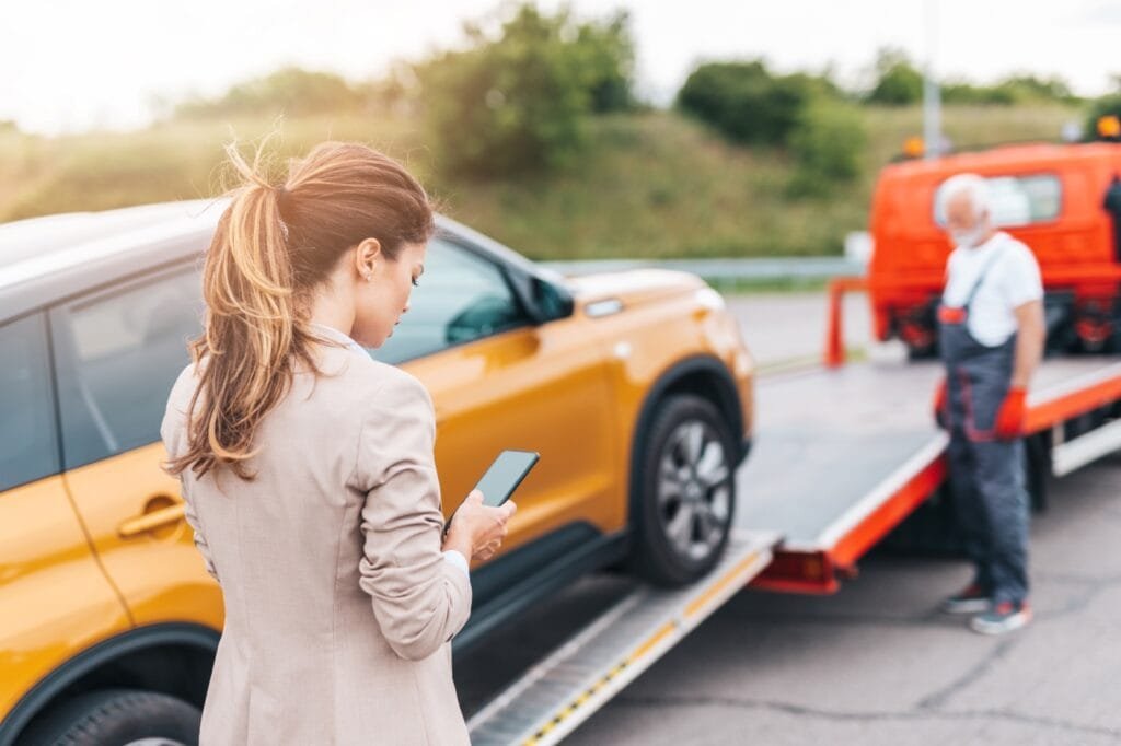 Tow Truck. A lady having her car connected to a tow truck for towing.
